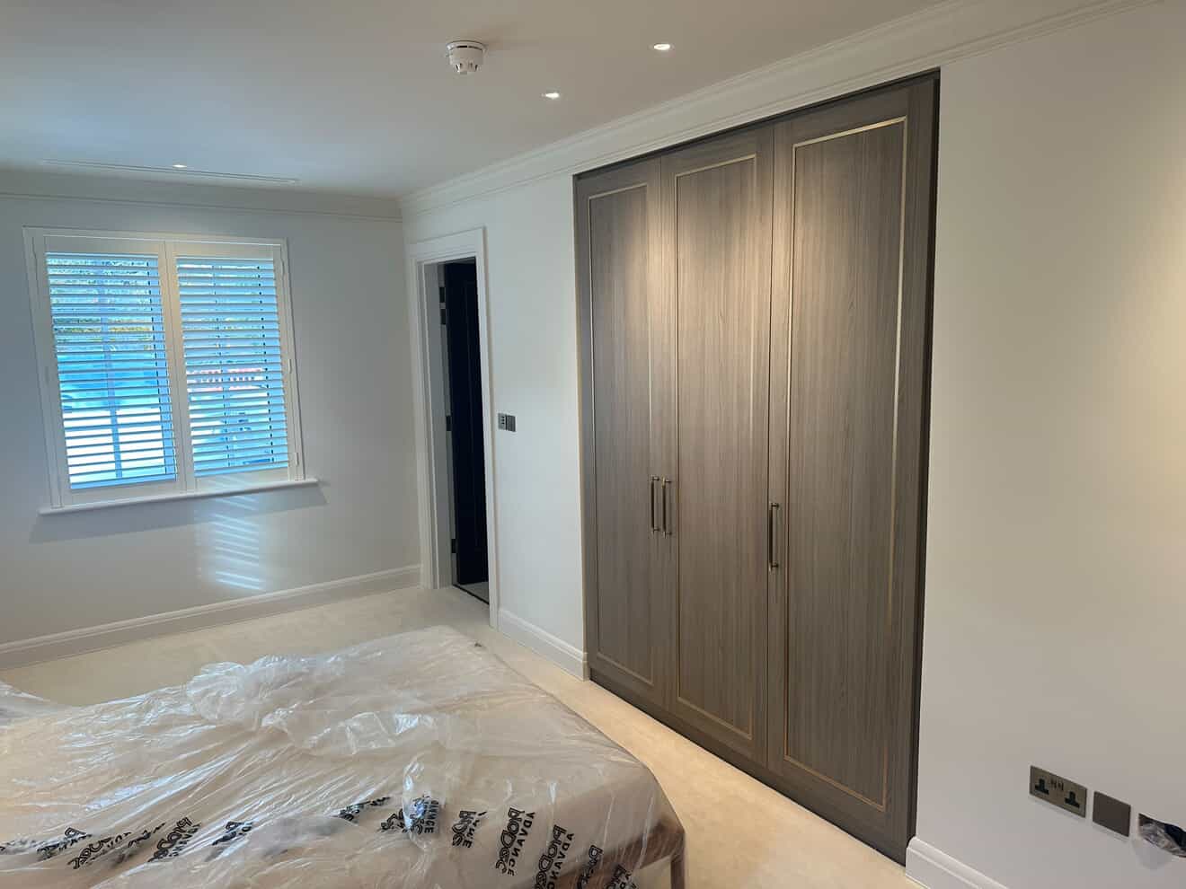 Bedroom with recessed downlights, fitted wardrobes and brushed chrome socket outlets