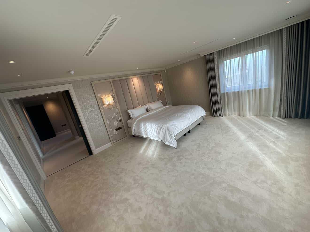 Luxury master bedroom with decorative wall sconces, padded headboard and LED downlights