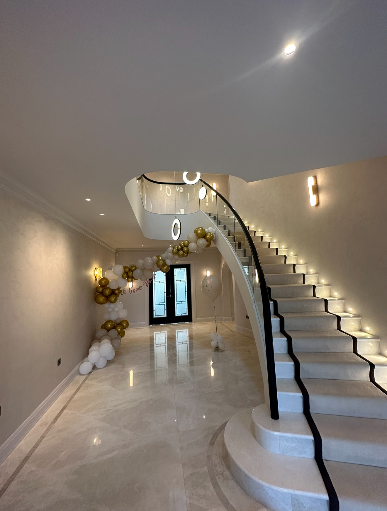 Grand hallway with curved staircase and luxury lighting installation by Lambourn Electrical Services in Surrey