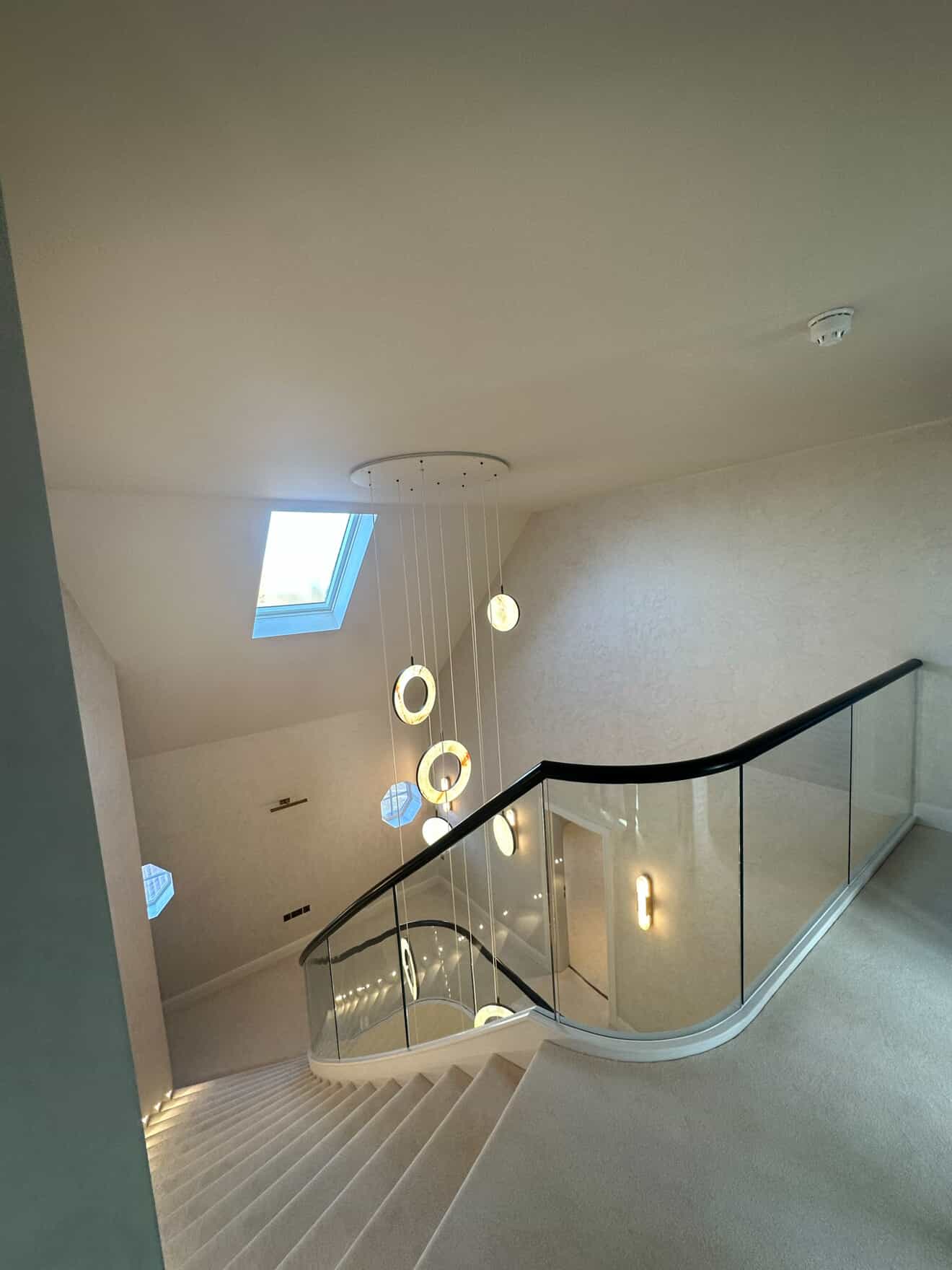 Multi-level pendant chandelier with ring lights viewed from staircase landing